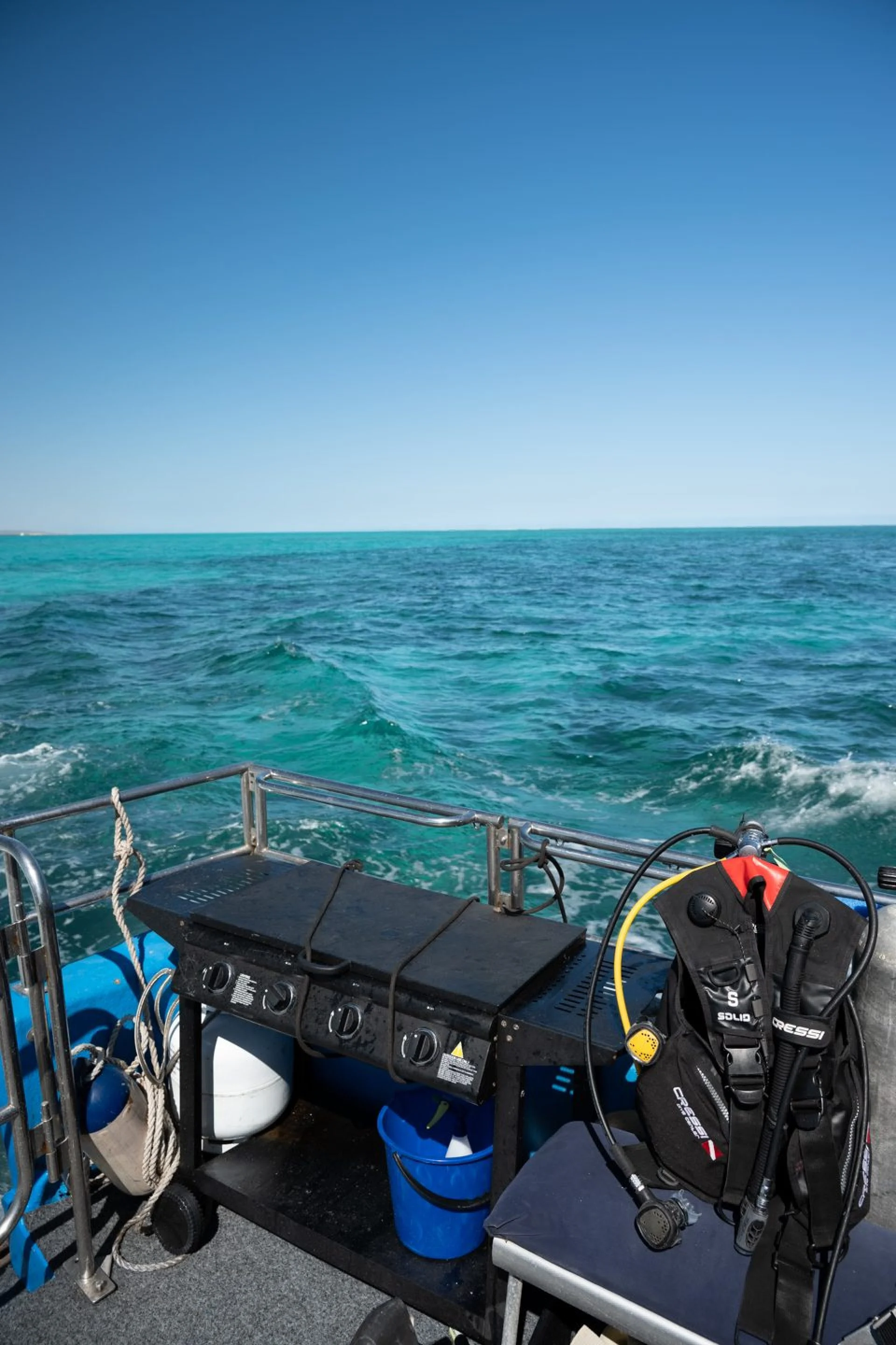 Boat deck with the BBQ and scuba gear over turquoise water