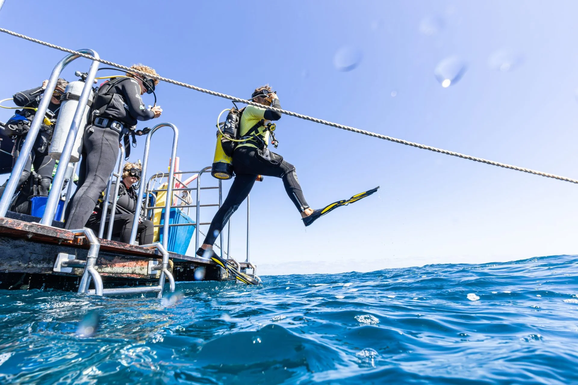 Half-underwater view of a diver giant-striding off the boat