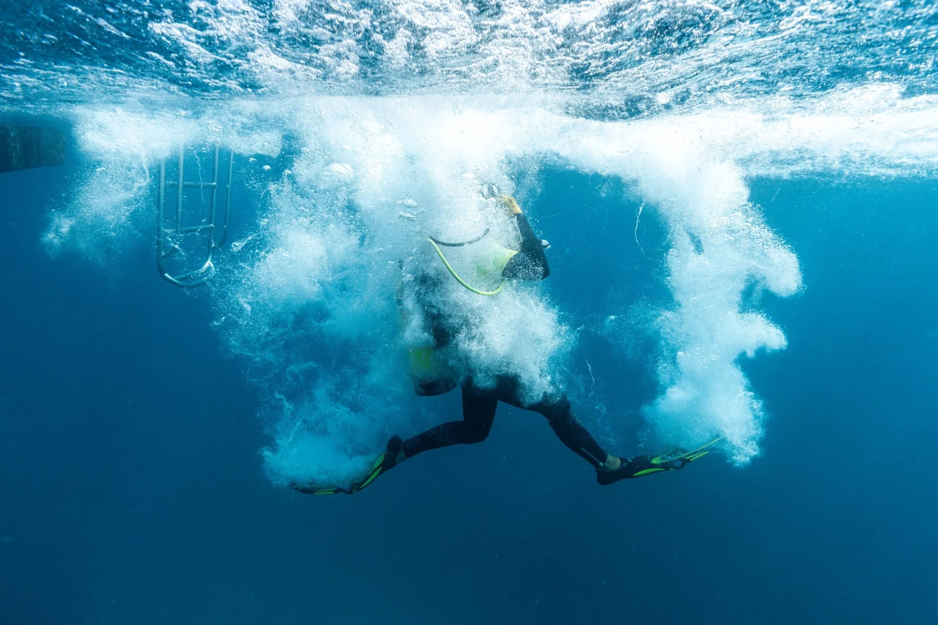 Diver plunging into the water surrounded by bubbles
